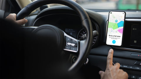 Smartphone mounted on car dashboard displaying Skipcart app with color-coded delivery zones map and "Go to a hot zone" interface, showcasing SirCharles.DESIGN's in-vehicle UX design for real-time route optimization and driver safety
